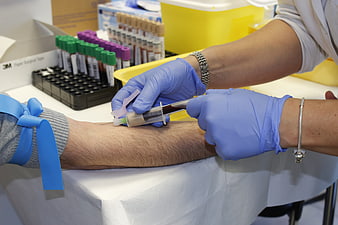 Medical professional drawing blood with syringe from patient arm