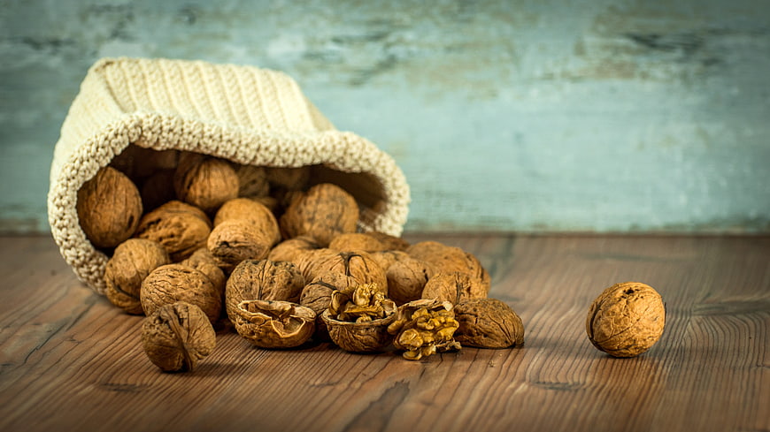 Walnuts Spilling from Knitted Bag on Wooden Table