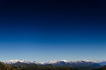 Snow-Capped Mountain Range Under Vast Blue Sky