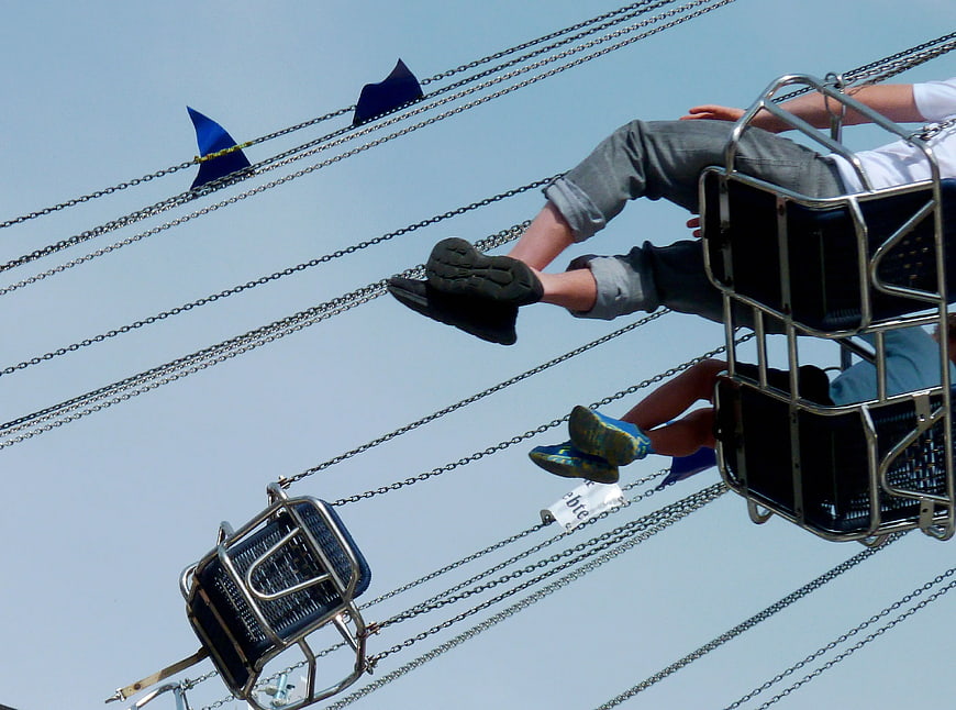 Low angle view of people on a swing ride against blue sky