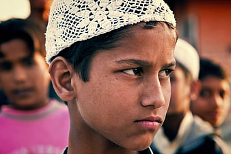 Close-up portrait of young Indian boy wearing white prayer cap