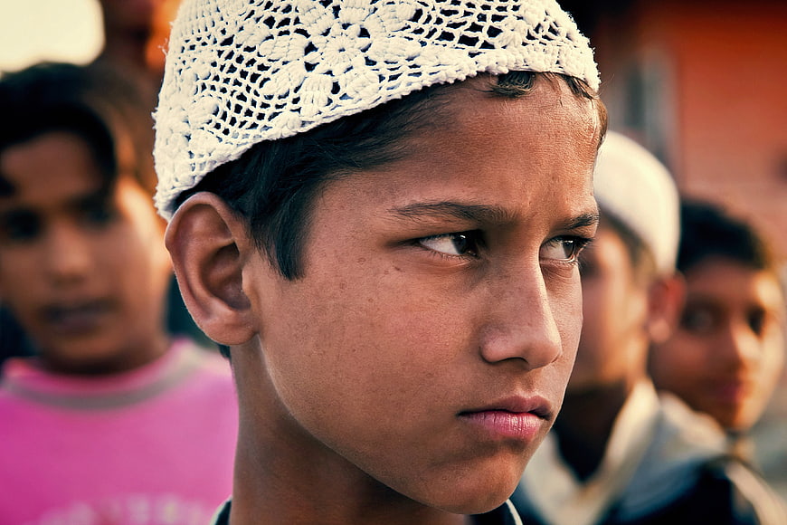 Close-up portrait of young Indian boy wearing white prayer cap