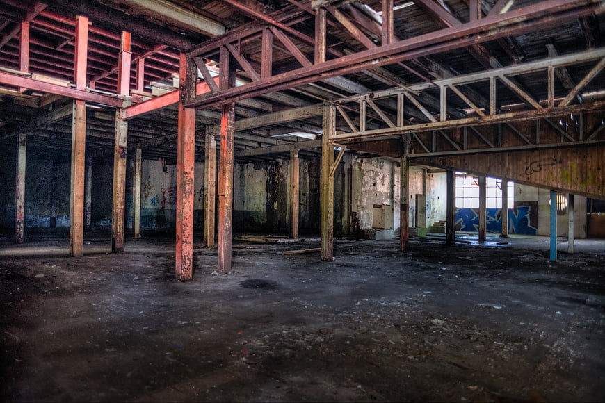 Abandoned industrial warehouse interior with rusty beams and graffiti