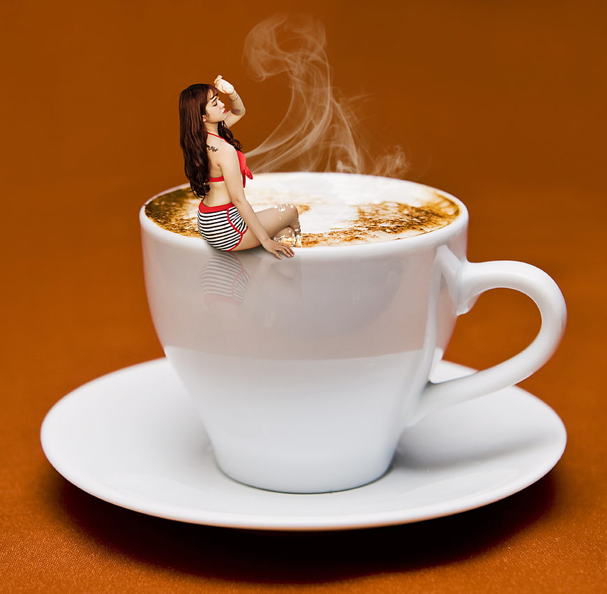 Woman in bikini sitting in a steaming white coffee cup