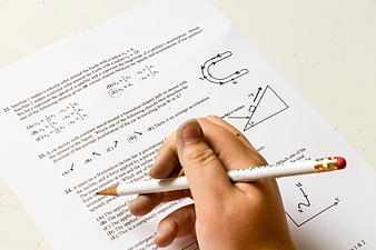 Hand holding pencil over physics exam paper