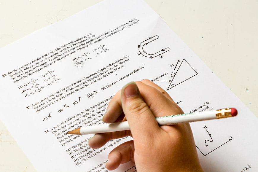 Hand holding pencil over physics exam paper