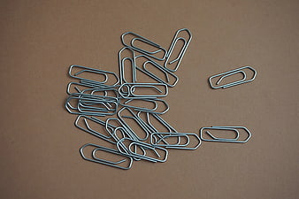 Scattered metal paper clips on brown background