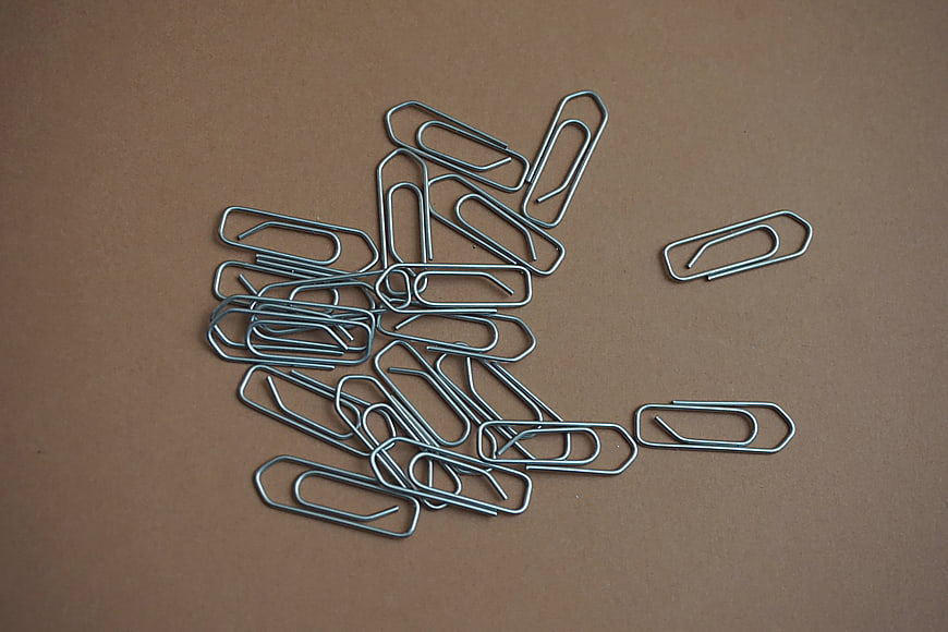 Scattered metal paper clips on brown background