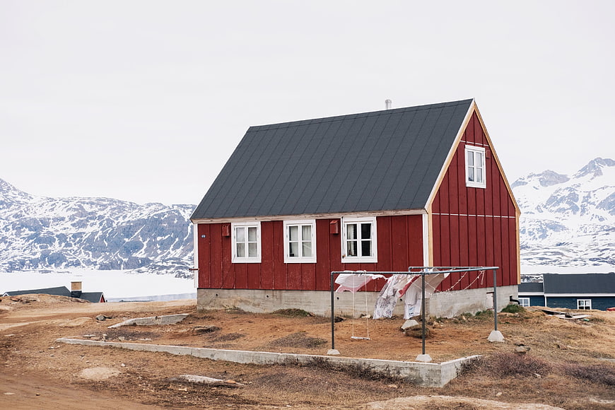 Red wooden house with mountains and laundry