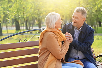 Happy Senior Couple Holding Hands on Park Bench
