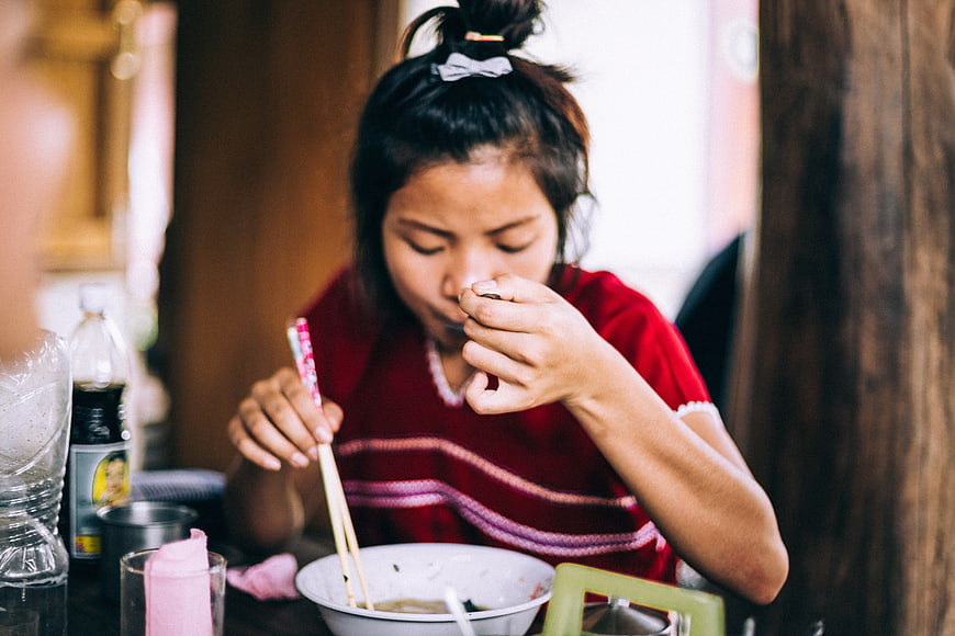 Asian woman eating noodles with chopsticks in restaurant