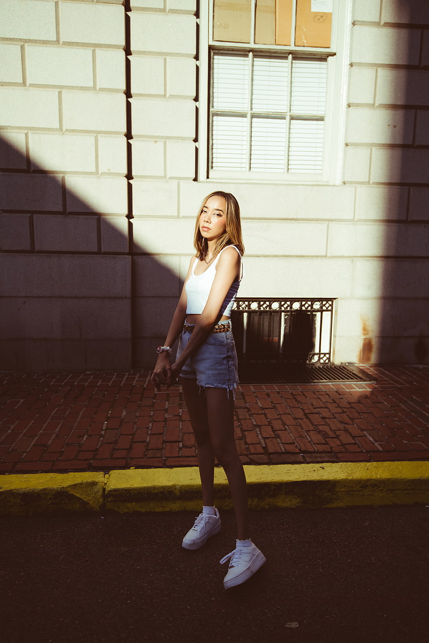 Young woman in white top and denim shorts standing on city street