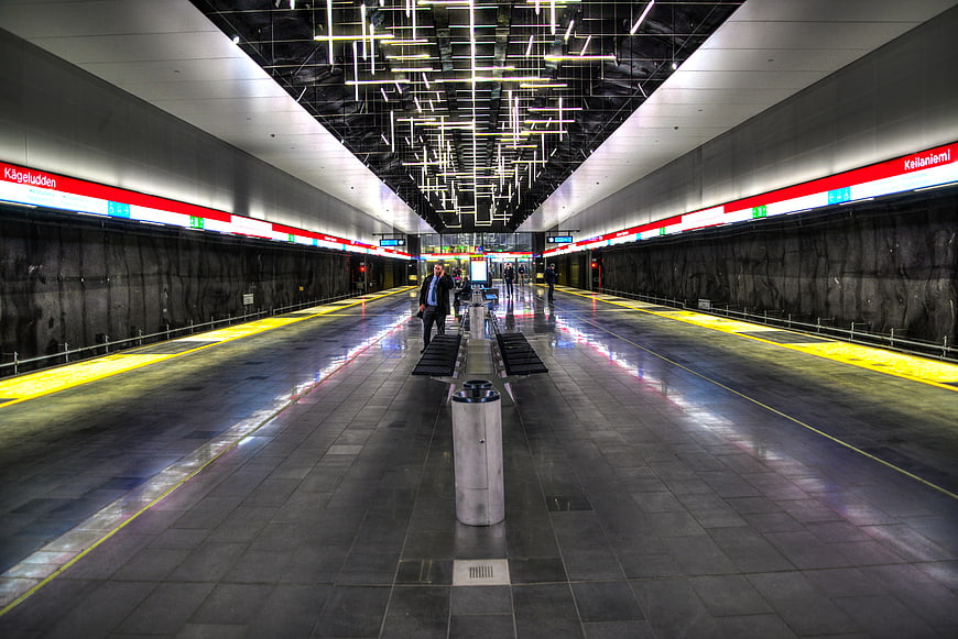 Modern Helsinki subway station with reflective floors and red signage