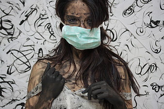 Woman with black body paint and medical mask against graffiti background