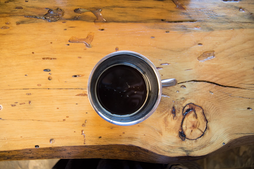 Top View of Black Coffee in Metal Cup on Rustic Wood Table