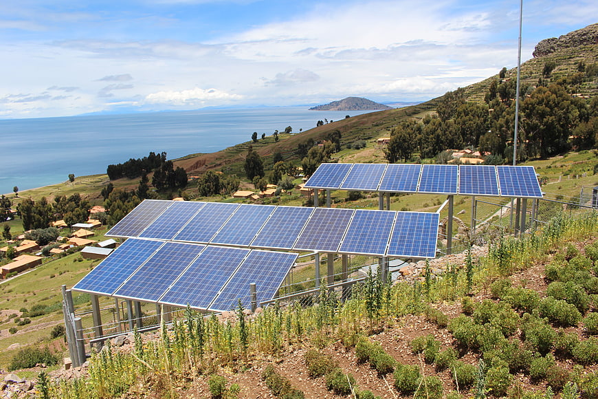 Solar panels on a hillside overlooking a large lake