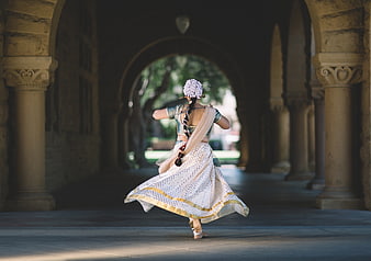 Woman in traditional Indian attire dancing in stone archway