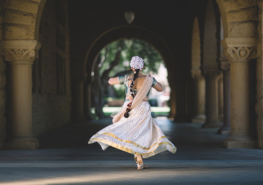 Woman in traditional Indian attire dancing in stone archway