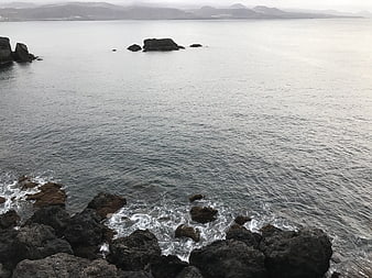 Serene coastal landscape with rocky shoreline and distant mountains
