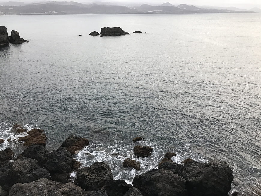Serene coastal landscape with rocky shoreline and distant mountains
