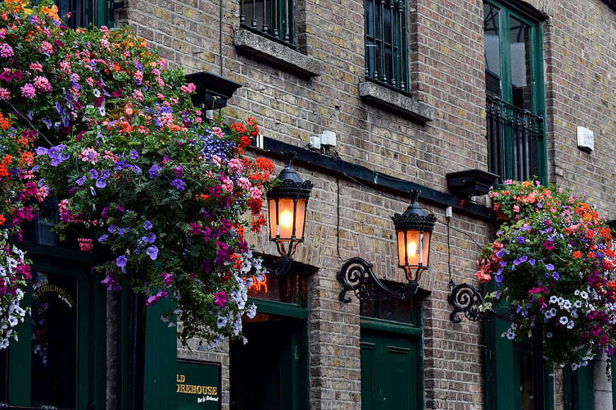 Colorful hanging flower baskets on historic brick pub facade