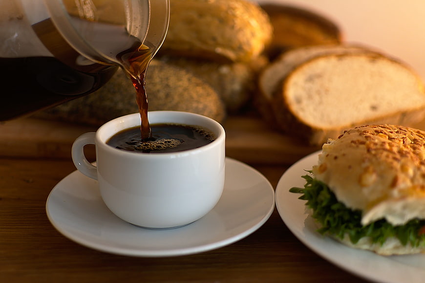 Pouring Coffee into White Cup with Sourdough Bread and Sandwich