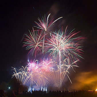 Colorful fireworks exploding over a crowd at night