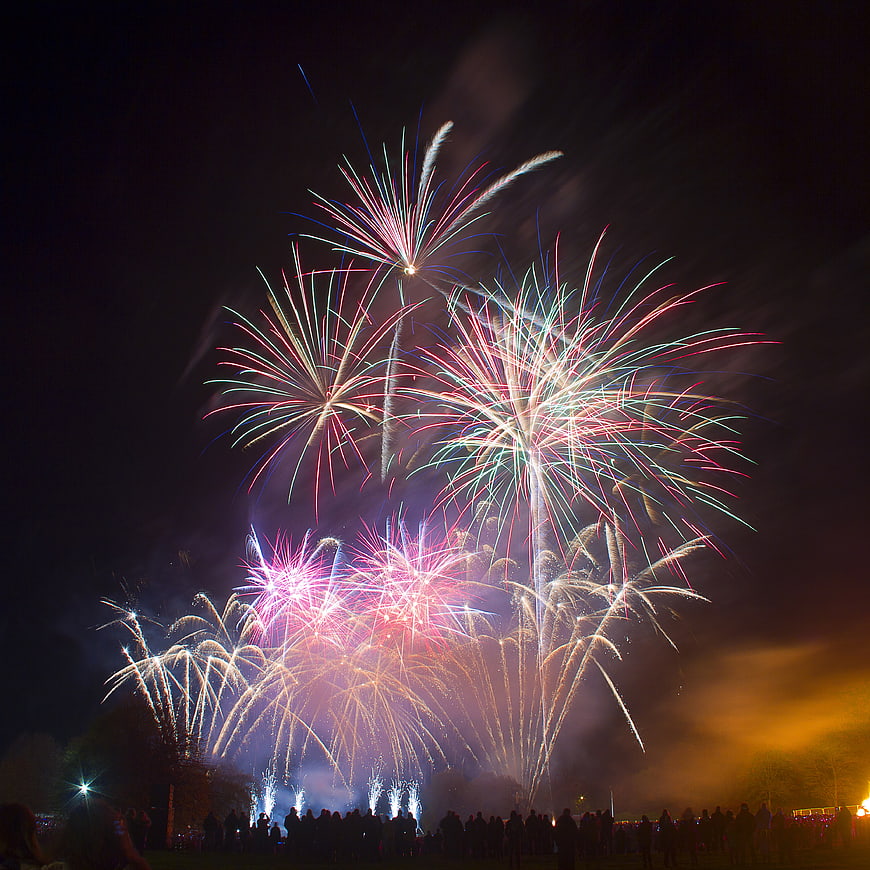 Colorful fireworks exploding over a crowd at night