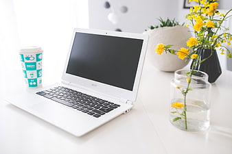 White laptop workspace with coffee and yellow flowers