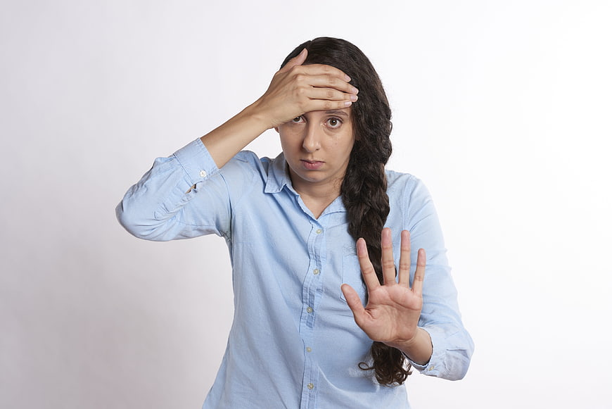 Frustrated woman holding hand up in stop gesture against white background