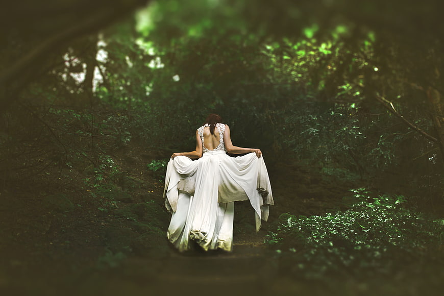Woman in White Dress Walking Away in Dark Forest