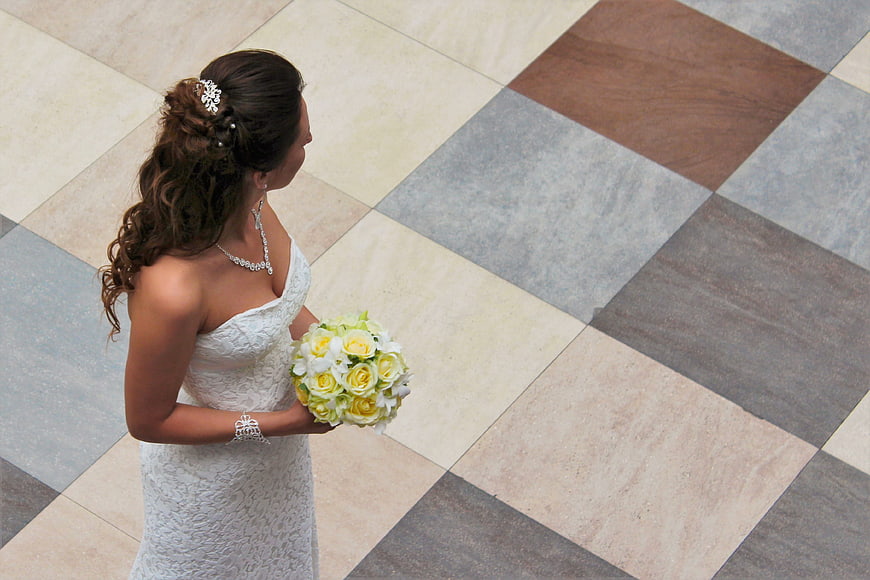 High angle view of bride holding yellow bouquet on tiled floor