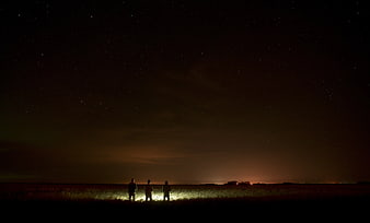 Three Silhouetted Figures Under Starry Night Sky