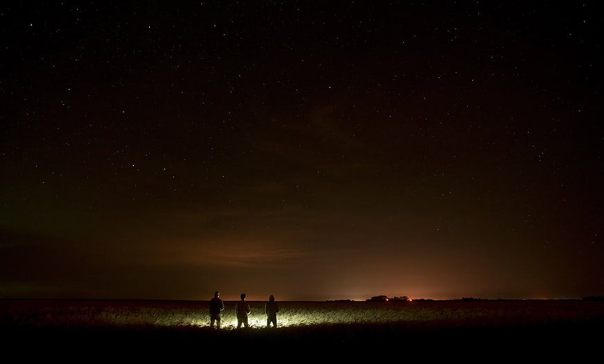 Three Silhouetted Figures Under Starry Night Sky