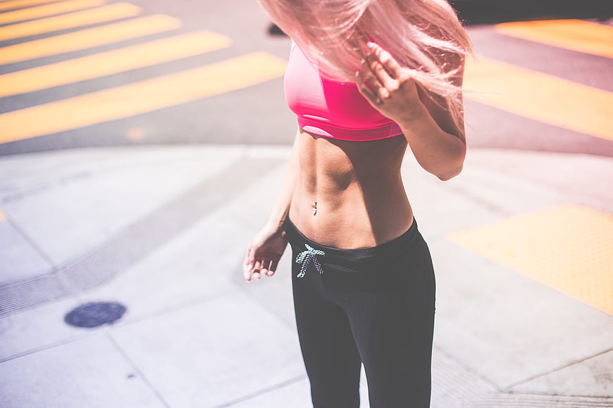 Fit Woman In Pink Sports Bra And Black Leggings On City Street