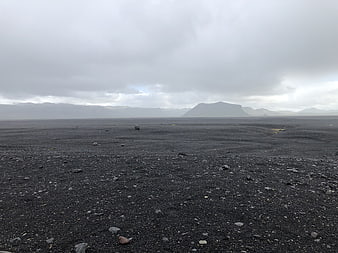 Vast black sand volcanic landscape with distant mountains