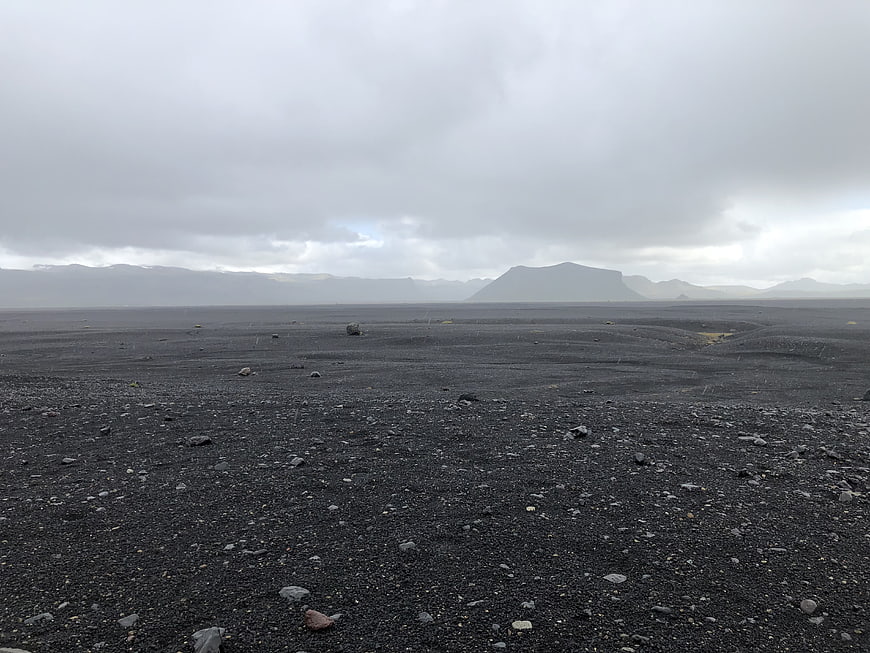 Vast black sand volcanic landscape with distant mountains