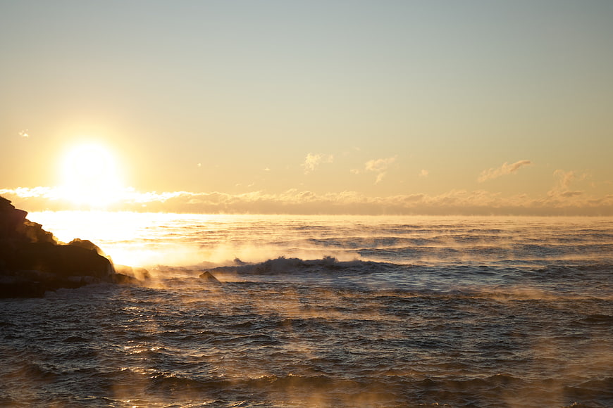 Golden Sunset Over Ocean Waves with Rocky Coastline