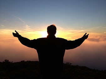 Silhouette of Man with Arms Raised at Sunset