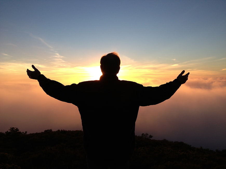 Silhouette of Man with Arms Raised at Sunset