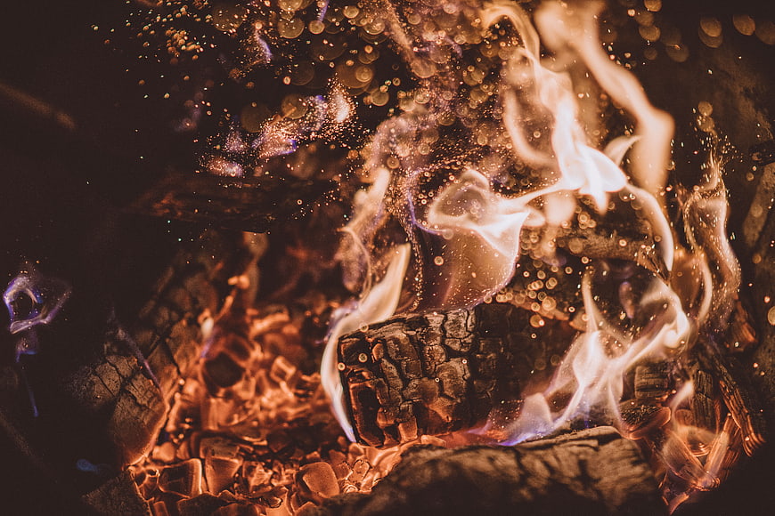 Close-up of burning firewood with glowing embers and sparks