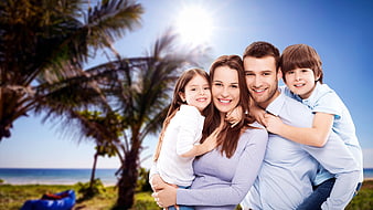 Happy family of four hugging on sunny tropical beach
