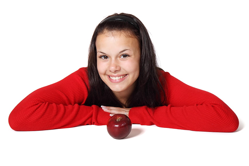 Smiling young woman with red apple on white background