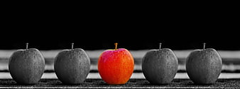 Red apple stands out among black and white apples