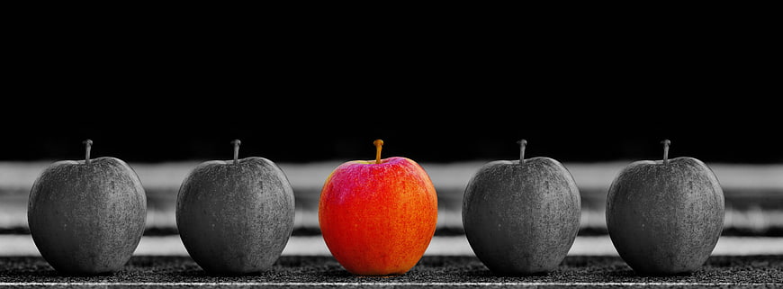 Red apple stands out among black and white apples