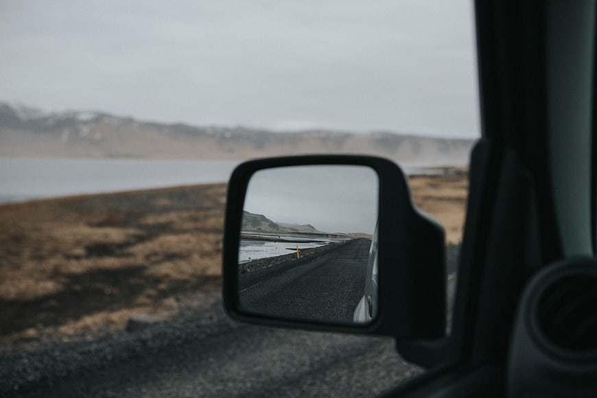 Road trip view through car side mirror with blurred landscape
