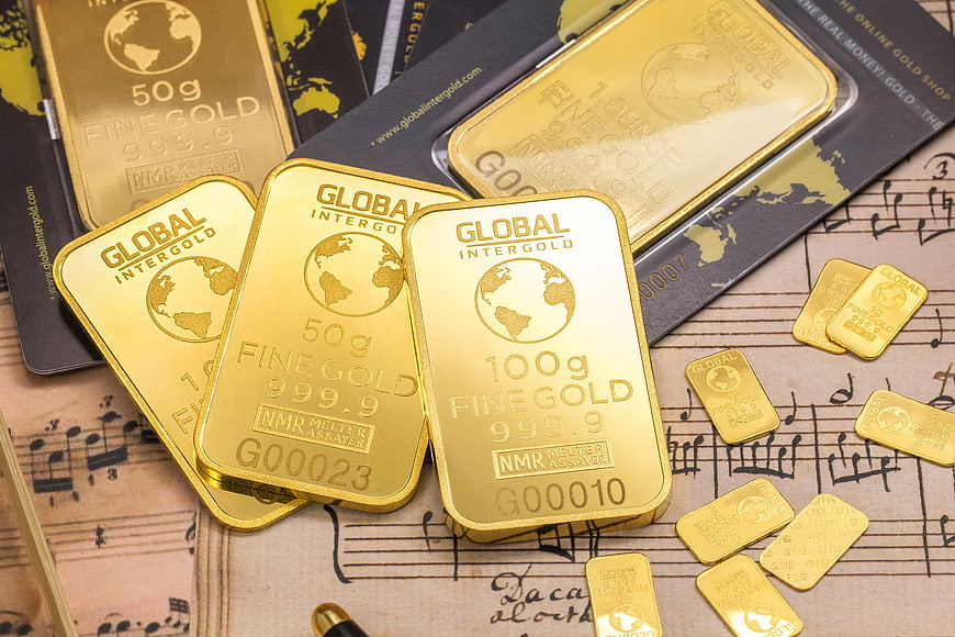 Gold bars and coins on vintage sheet music background