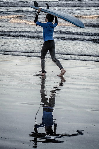Surfer Walking on Beach with Blue Surfboard