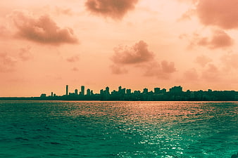 Teal and Orange City Skyline at Sunset Over Ocean