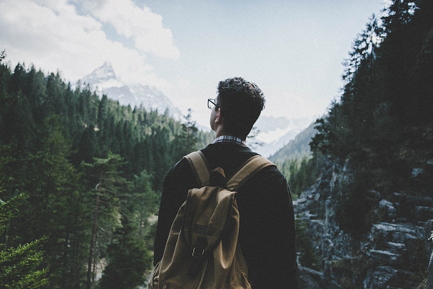 Man with Backpack Looking at Mountain Landscape